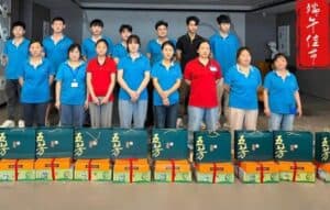 Team of event staff wearing blue and red shirts, standing behind gift boxes during corporate event.