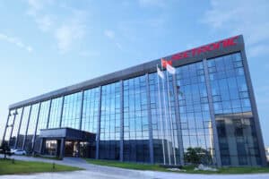 Modern glass office building with Seetronic signage and flags in front.
