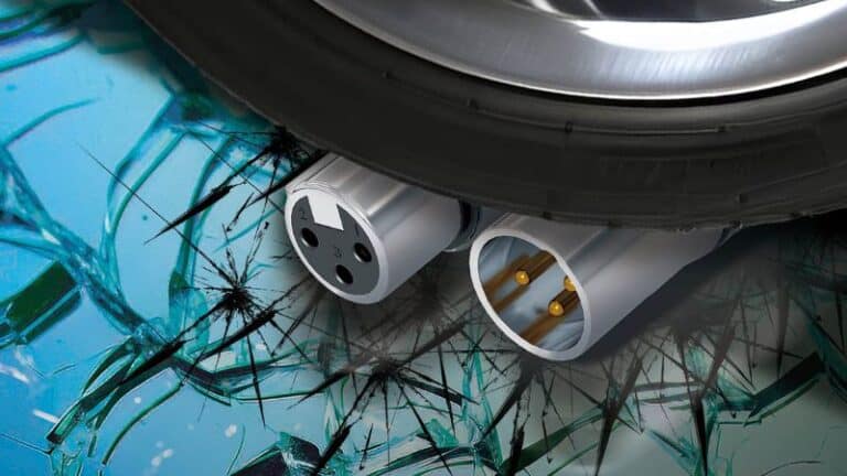 Broken electrical outlet with shattered glass on reflective surface, emphasizing electrical hazards and safety risks.