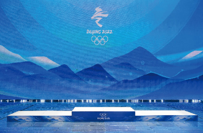 Beijing 2022 Winter Olympics stage with mountains and Olympic logo.